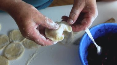 Yaşlı bir kadın hamurdan hamur köftesi ve krep heykeli yapar, mutfakta buğday unundan, yaşam tarzından yemek pişirir. Hamur köftesi heykeli. Ev yapımı gıda konsepti