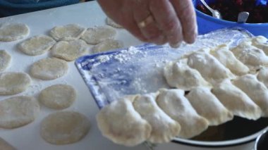 Yaşlı bir kadın hamurdan hamur köftesi ve krep heykeli yapar, mutfakta buğday unundan, yaşam tarzından yemek pişirir. Hamur köftesi heykeli. Ev yemeği konsepti