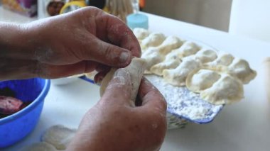 Bir kadın hamur hamuruyla hamur köftesi heykeli yapıyor, mutfakta buğday unundan, yaşam tarzından yemek pişiriyor. Hamur köftesi heykeli. Ev yapımı yemek pişirme kavramı