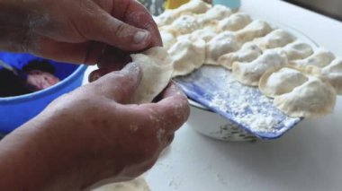 Bir kadın hamur hamuruyla hamur köftesi heykeli yapıyor, mutfakta buğday unundan, yaşam tarzından yemek pişiriyor. Hamur köftesi heykeli. Ev yapımı yemek pişirme kavramı