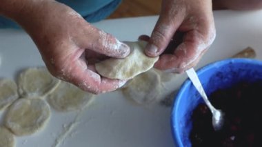 Bir kadın hamur hamuruyla hamur köftesi heykeli yapıyor, mutfakta buğday unundan, yaşam tarzından yemek pişiriyor. Hamur köftesi heykeli. Ev yapımı gıda konsepti.