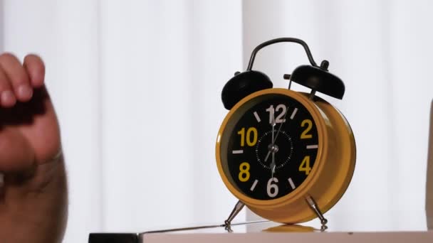 目覚まし時計はベッドで寝ている人を起こします レトロな目覚まし時計リング 午前中に手で時計を反転 午前6時 眠っている人の朝起きる — ストック動画