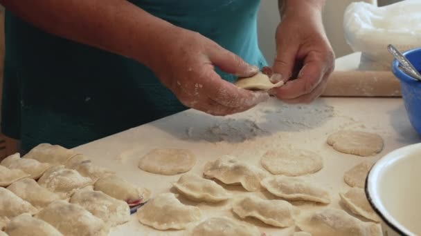 一位老年妇女用面团做饺子和煎饼 用天然小麦粉在厨房里做饭 生活方式 做饺子 家庭食品概念 — 图库视频影像
