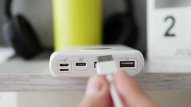 Güç bankası şarj oluyor, USB kablosunu güç bankası bağlantısına takın. Bir adam akıllı telefonu elektrik bankasından şarj ediyor..