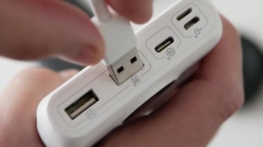 Üst görüntü, USB priziyle şarj olan güç bankası kablosu güç bankası konnektörüne takılacak. Bir adam akıllı telefonu elektrik bankasından şarj ediyor..