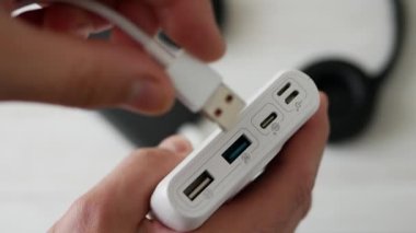 Güç bankası USB priziyle şarj oluyor, USB kablosunu güç bankasının konnektörüne takın. Bir adam akıllı telefonu elektrik bankasından şarj ediyor.