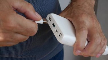 Yaşlı bir adam elektrik bankasından akıllı telefonu şarj eder, bir adam da enerji bankasından bir cihaz şarj eder. Aküde Usb yuvası