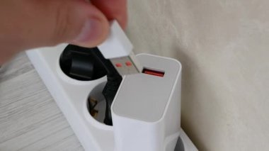 Adamın biri USB kablosundan akıllı telefonu şarj ediyor. Kabloyu şarj cihazına yerleştirirsen, kişi güç kaynağından cihazı şarj edecek..