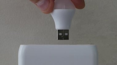Aydınlatma, şarj istasyonundaki bir lambanın parıltısı, bir insan pilin içine bir USB ampul yerleştirir. Yakın çekim için enerji tasarrufu lambası