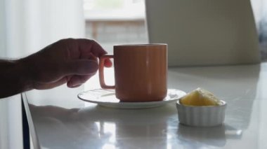 Mutfak masasında sıcak çay, yaşlı bir adam limonlu çay içer. Buharlı romatik çay, ev yapımı içecek.