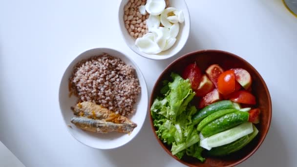荞麦粥与煮熟的鱼共进晚餐 煮豆子与蛋清 蔬菜沙拉在盘子里 健康的自制食物 西红柿在盘子里 — 图库视频影像
