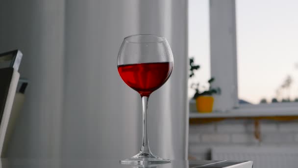 窓の背景に光沢のあるテーブルの上に赤ワインとワイングラス アロマティックワイン グラスにアルコール — ストック動画