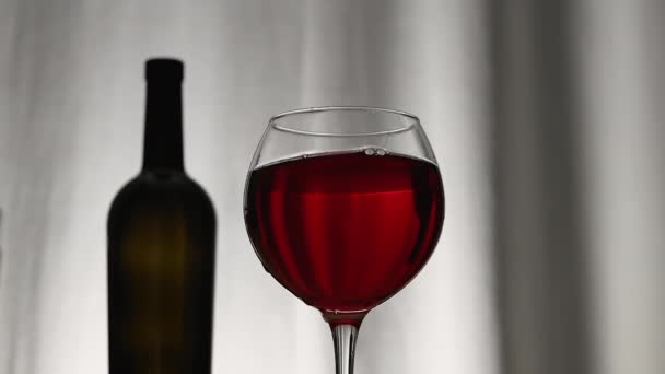 ヴェロールカーテンを背景に赤ワインをグラスにしたワインボトルのシルエット ワイングラスでカールワインの撮影 — ストック動画