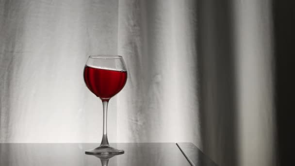 クローズアップ ベロールカーテンの背景に対してグラスに赤ワイン ワイングラスにグレープワイン アルコールドリンクレッド — ストック動画
