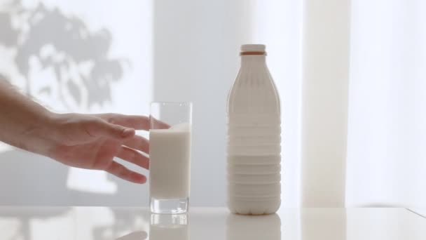 一个男人把一杯牛奶放在白色的背景上 牛奶放在塑料瓶里 生活方式 牛奶早餐 — 图库视频影像