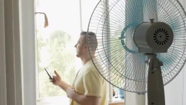 Knappe Jongeman Het Appartement Wordt Gekoeld Door Een Ventilator Van — Stockvideo