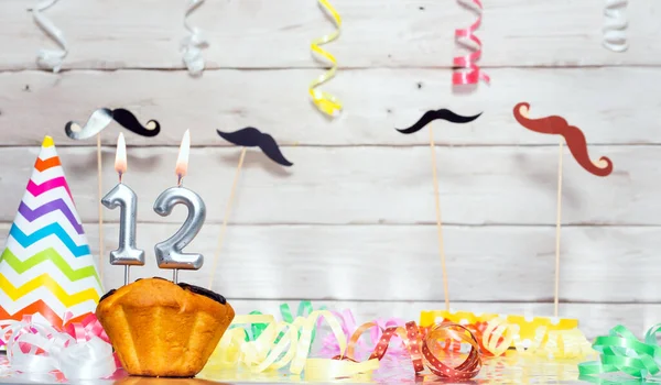 Birthday with number  12. Date of birth with number and candles, copy space. Anniversary background with cake or muffin with burning candles. Keative postcard congratulations.