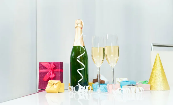 Date of birth with a bottle of champagne. Festive Champagne in glasses with gift boxes, anniversary card, happy birthday decorations