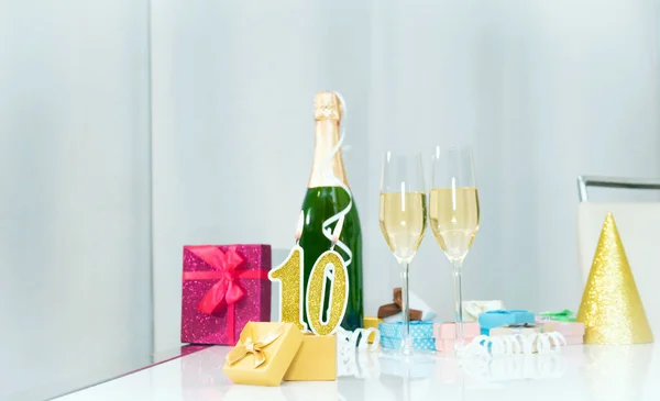 Date of birth with number  10. Festive Champagne in glasses with gift boxes, anniversary postcard. Happy birthday golden candles.