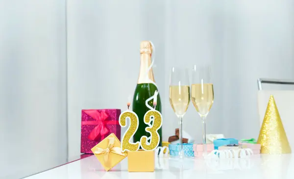 Date of birth with number  23. Festive Champagne in glasses with gift boxes, anniversary postcard. Happy birthday golden candles.