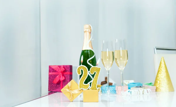 Date of birth with number  27. Festive Champagne in glasses with gift boxes, anniversary postcard. Happy birthday golden candles.