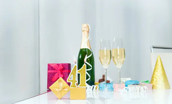 Date of birth with number  41. Festive Champagne in glasses with gift boxes, anniversary postcard. Happy birthday golden candles.