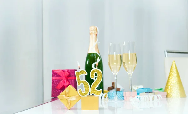 Date of birth with number  52. Festive Champagne in glasses with gift boxes, anniversary postcard. Happy birthday golden candles.