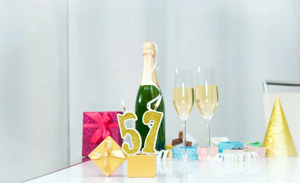 Date of birth with number  57. Festive Champagne in glasses with gift boxes, anniversary postcard. Happy birthday golden candles.