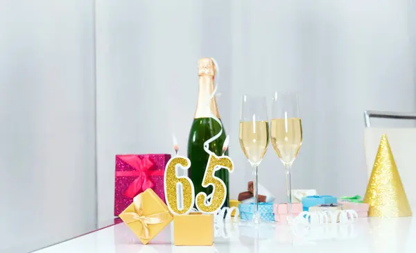 Date of birth with number  65. Festive Champagne in glasses with gift boxes, anniversary postcard. Happy birthday golden candles.