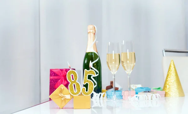 Date of birth with number  85. Festive Champagne in glasses with gift boxes, anniversary postcard. Happy birthday golden candles.