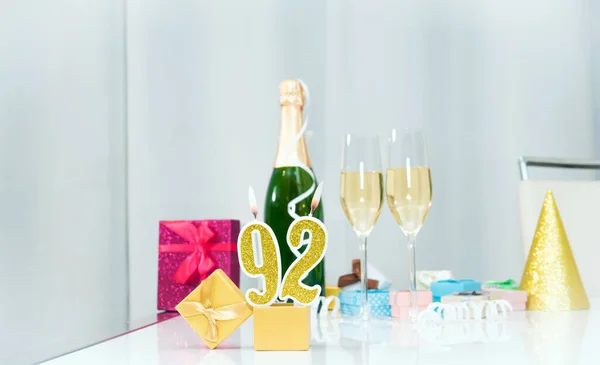 Date of birth with number  92. Festive Champagne in glasses with gift boxes, anniversary postcard. Happy birthday golden candles.