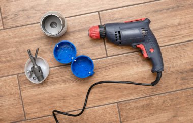 Elektrik prizlerini delmek için matkapla delmek. Duvarı delmek için inşaat aletleri. Plastik soket kutusu.