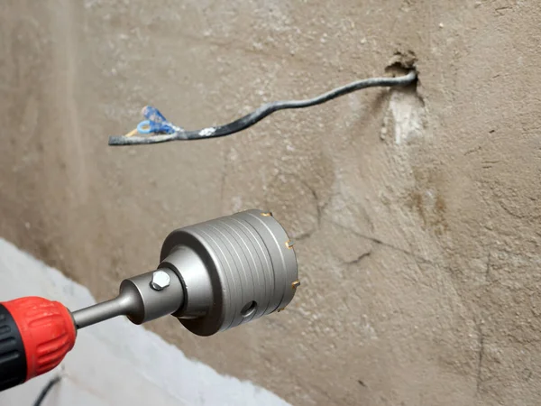 Installation of sockets in the house. A hammer drill with a drill for drilling electrical sockets. Construction tools for drilling in a brick wall.