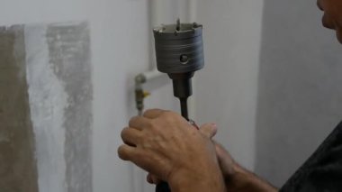 Matkabı betona sok. Bir erkek işçi elinde matkapla duvarda bir oyuk açıyor. Daireye bir elektrik prizi kuruluyor..