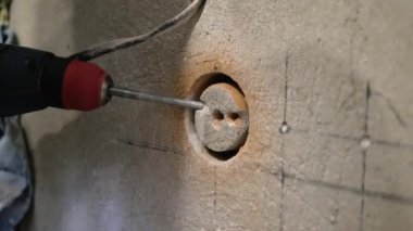  Becerikli bir adam, elinde matkapla çalışan bir erkek işçi için ağda delik açıyor. Daireye bir elektrik prizi kurulmuş. Çekirdek sondajları devam ediyor.