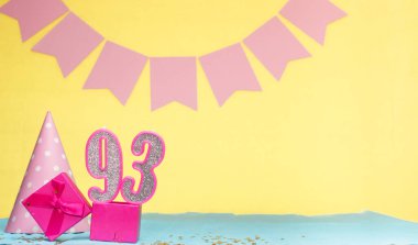 93 yaşında bir kızın doğum tarihi. Uzayı kopyala Sarı arkaplanlı pembe gözlüklü bir doğum günü. Üzerinde numaralandırılmış mumlar ve hediye kutusu olan dekorasyonlar. Bir kadın için yıldönümü kartı