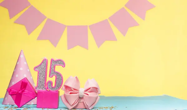 Date of birth for a girl  15. Copy space. Birthday in pink shades with a yellow background. Decorations with numbered candles and a gift box. Anniversary card for a woman