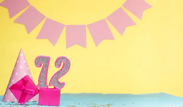 Date of birth for a girl  72. Copy space. Birthday in pink shades with a yellow background. Decorations with numbered candles and a gift box. Anniversary card for a woman