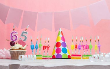 Geçmiş doğum tarihi 65 numara. Yıldönümü. Bir kız için mumlarla dolu güzel bir arka plan. Kadınların tebrik kartı. Pembeli mutlu yıllar..