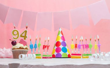 Geçmişi doğum tarihi 94. Yıldönümü. Bir kız için mumlarla dolu güzel bir arka plan. Kadınların tebrik kartı. Pembeli mutlu yıllar..