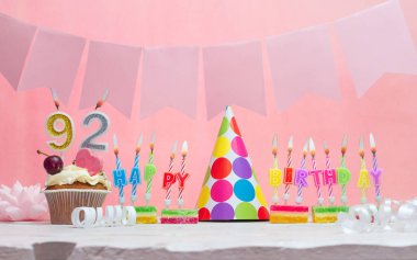 Doğum tarihi 92 'ydi. Yıldönümü. Bir kız için mumlarla dolu güzel bir arka plan. Kadınların tebrik kartı. Pembeli mutlu yıllar..