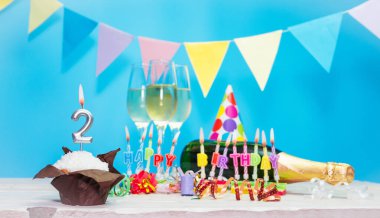 Doğum tarihi, mumlar ve 2 numara. Yıldönümü tebrik kartı. Tatil süslemeleri. Mutlu doğum günü mumları. Çok renkli çelenklerle süslenmiş.