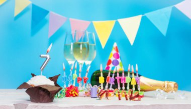 Doğum tarihi, mumlar ve 7 numara. Yıldönümü tebrik kartı. Tatil süslemeleri. Mutlu doğum günü mumları. Çok renkli çelenklerle süslenmiş.