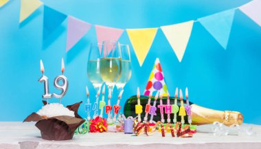 Doğum tarihi, mumlar ve 19 numara. Yıldönümü tebrik kartı. Tatil süslemeleri. Mutlu doğum günü mumları. Çok renkli çelenklerle süslenmiş.