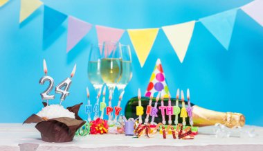 Doğum tarihi, mumlar ve 24 numara. Yıldönümü tebrik kartı. Tatil süslemeleri. Mutlu doğum günü mumları. Çok renkli çelenklerle süslenmiş.