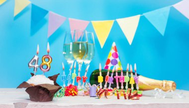 Doğum tarihi, mumlar ve 48 numara. Yıldönümü tebrik kartı. Tatil süslemeleri. Mutlu doğum günü mumları. Çok renkli çelenklerle süslenmiş.