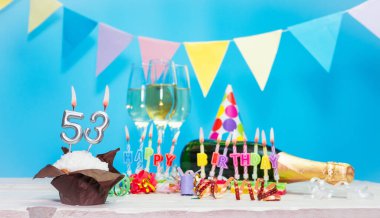 Doğum tarihi, mumlar ve 53 numara. Yıldönümü tebrik kartı. Tatil süslemeleri. Mutlu doğum günü mumları. Çok renkli çelenklerle süslenmiş.