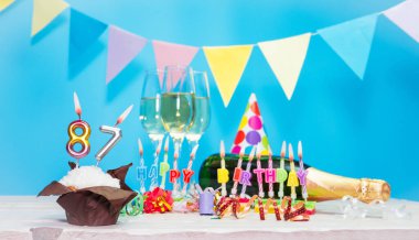 Doğum tarihi, mumlar ve 87 numara. Yıldönümü tebrik kartı. Tatil süslemeleri. Mutlu doğum günü mumları. Çok renkli çelenklerle süslenmiş.