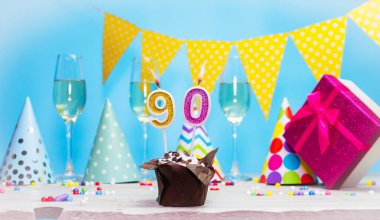 Doğum günü kutulu bir kadın ya da kız için doğum tarihi. Mum sayısı 90 olan turta. Yıldönümü kartı ve şampanya. Tatil süslemeleri. Mutlu yıllar.