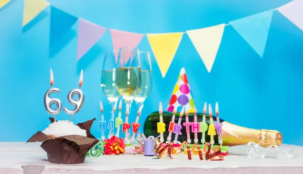 Doğum tarihi, mumlar ve 69 numara. Yıldönümü tebrik kartı. Tatil süslemeleri. Mutlu doğum günü mumları. Çok renkli çelenklerle süslenmiş.